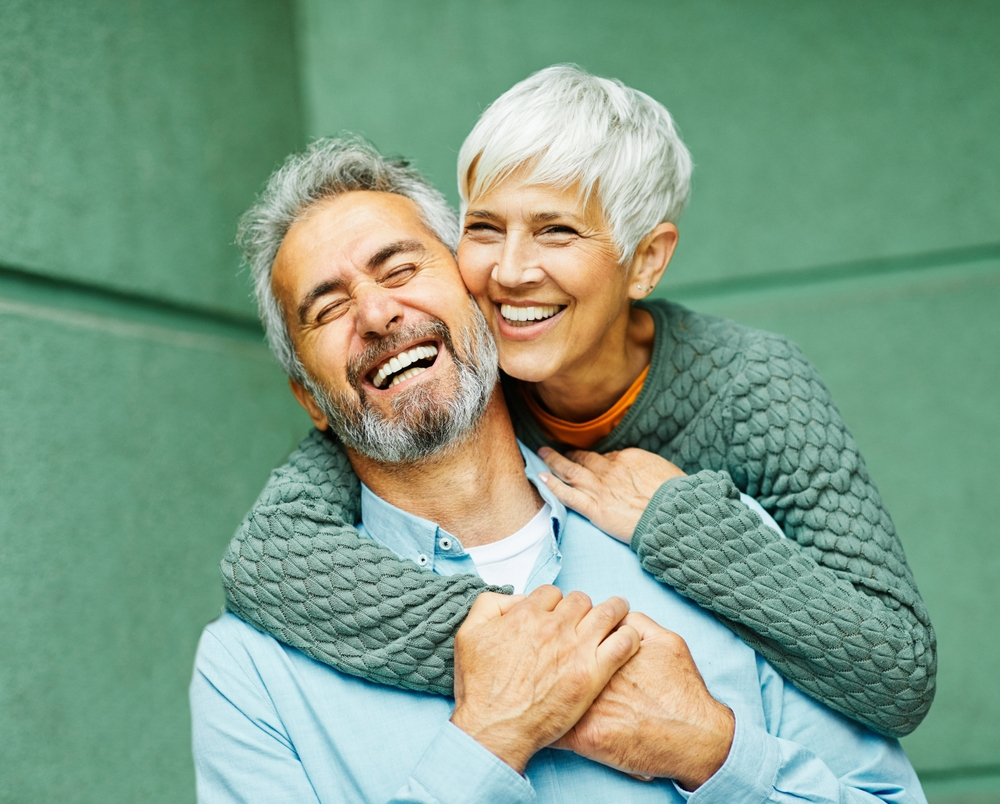 Senior couple smiling in front of green wall
